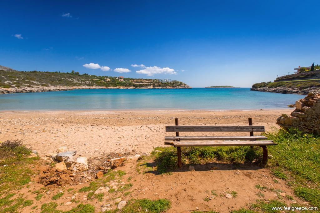 Lonely bench on a sandy beach with blue sea