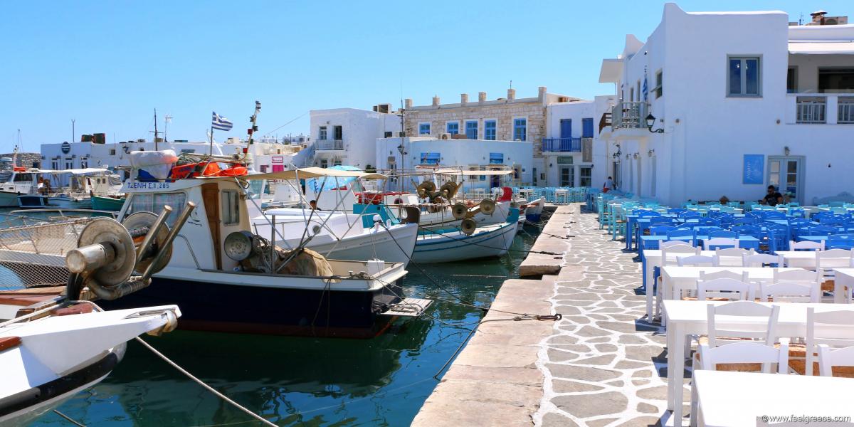Traditional Cycladic fishing harbor with tavernas and fishing boats in front